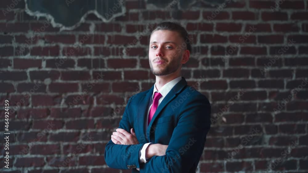 Stylish young businessman portrait standing indoor hands crossed dressed business suit smiling at camera Handsome caucasian male business person red brick wall background serious than smile Stylish young businessman portrait standing indoor hands crossed dressed business suit smiling at camera Handsome caucasian male business person red brick wall background serious than smile