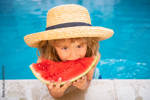 Funny child plays in the pool. The child eats a sweet watermelon, enjoy the summer. Carefree childhood.