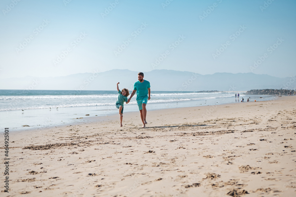 Father and son running on summer beach. Dad and child playing outdoor.