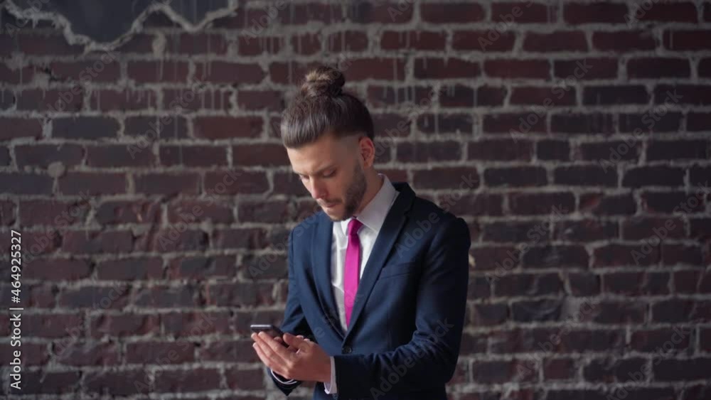 Surprised businessman reading good news on phone indoor red brick wall background. Portrait shoot dancing happy male professional enjoying success. Handsome business man dance dressed business suit Surprised businessman reading good news on phone indoor red brick wall background. Portrait shoot dancing happy male professional enjoying success. Handsome business man dance dressed business suit