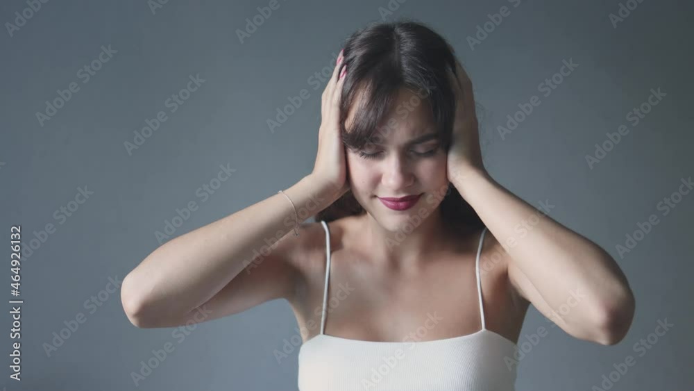 beautiful young woman eyes closed covering ears with hands and shaking head suffering from loud noise or headache. pretty female brunette fringe showing don't want to listen. upset girl can't hear. beautiful young woman eyes closed covering ears with hands and shaking head suffering from loud noise or headache. pretty female brunette fringe showing don't want to listen. upset girl can't hear.
