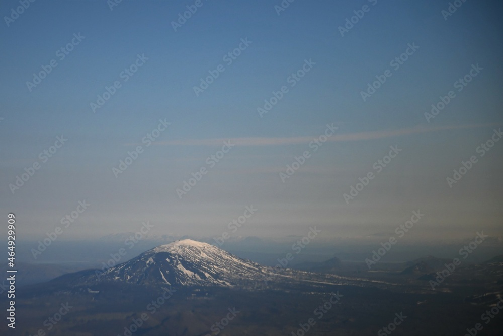 Hekla volcano, Iceland, snow-capped mountain beneath a dusky blue sky with white clouds.