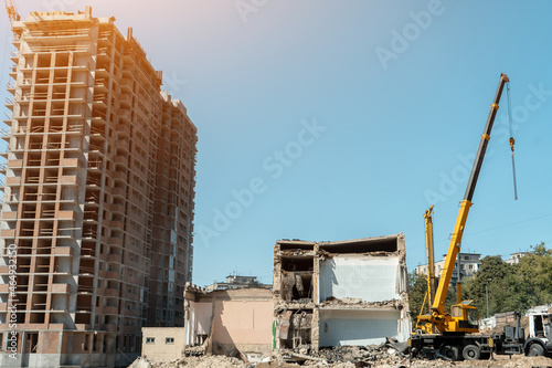 Canvas-taulu crane and demolition of old building near new construction of modern skyscraper