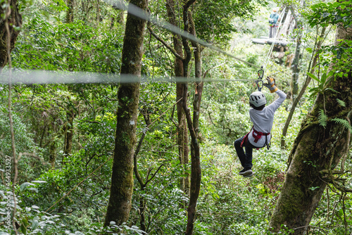 Joven adolescente colgando de cables para canopy en la selva de costa rica 