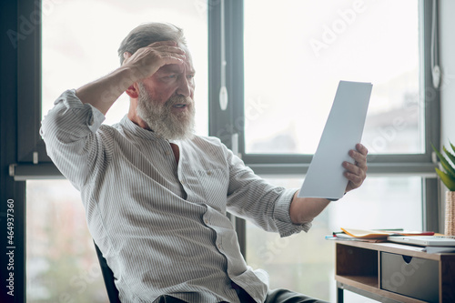 A midaged businessman holding papers and ecrutinizing them photo