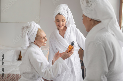 Women in bathrobes discussing new cosmetic product