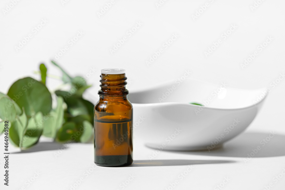 Bottle of essential oil and bowl on light background Bottle of essential oil and bowl on light background