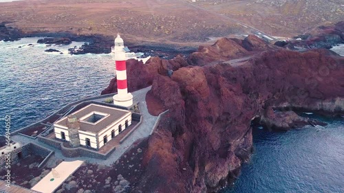 Red and white lighthouse in Punta De Teno, Tenerife, aerial orbit view photo