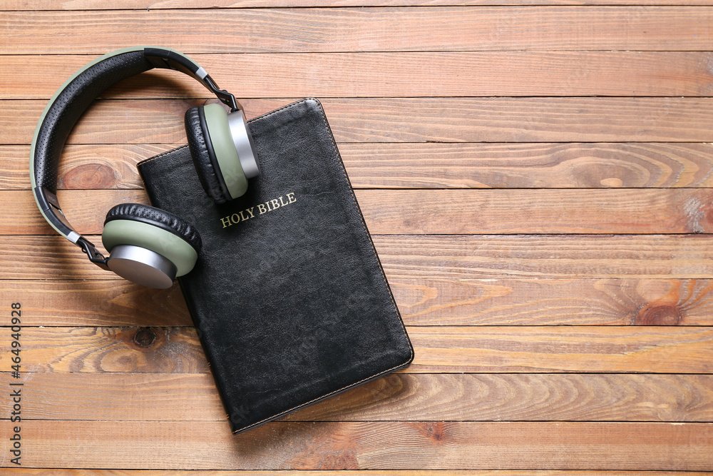Holy Bible and modern headphones on wooden background Holy Bible and modern headphones on wooden background