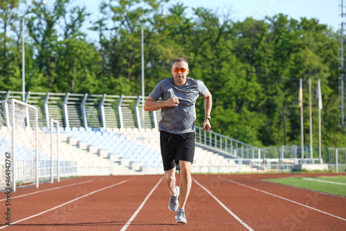 Sporty mature man jogging at stadium