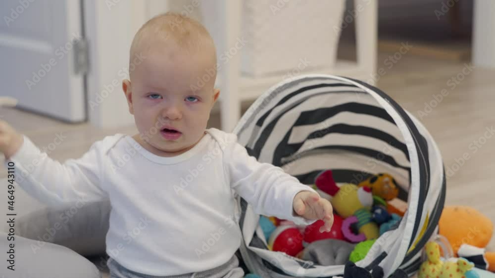 Baby sitting on the floor playing with toys from toy storage basket, cute 7 month old baby boy having fun exploring new world around him at home. High quality 4k footage Baby sitting on the floor playing with toys from toy storage basket, cute 7 month old baby boy having fun exploring new world around him at home. High quality 4k footage