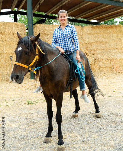 Positive woman farmer riding a horse. High quality photo