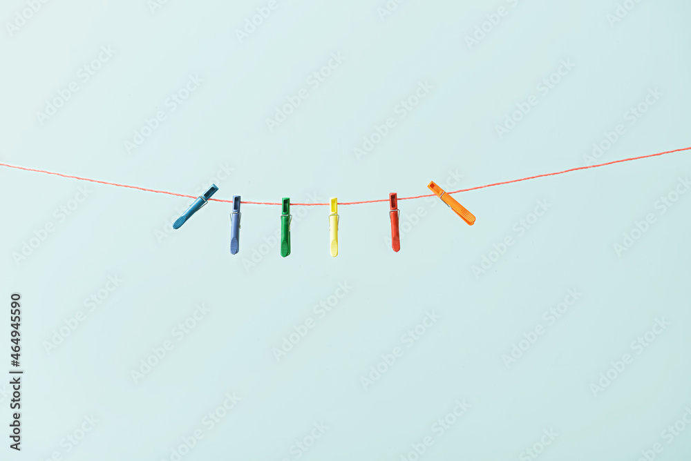 Many clothespins hanging on rope against blue background Many clothespins hanging on rope against blue background