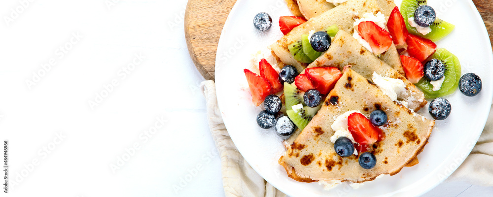 Sweet crepes with berries and cream on white wooden background. Sweet crepes with berries and cream on white wooden background.