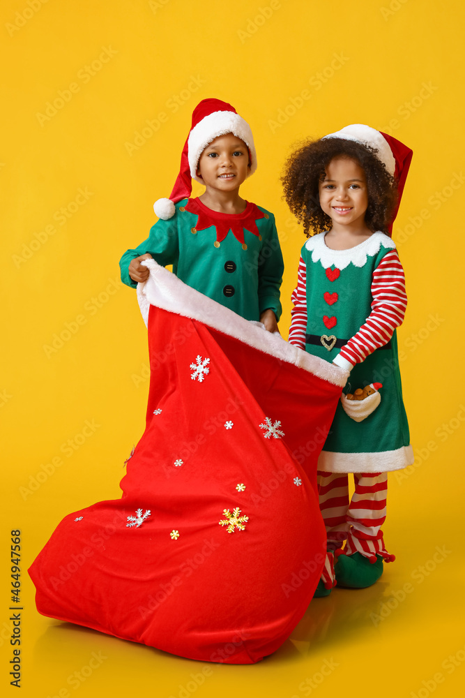 Cute little elves with Santa bag on yellow background