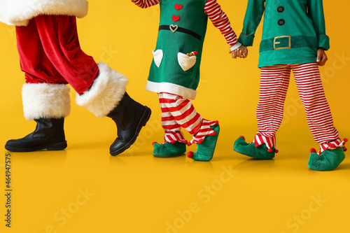 Legs of Santa Claus and little elves on yellow background photo
