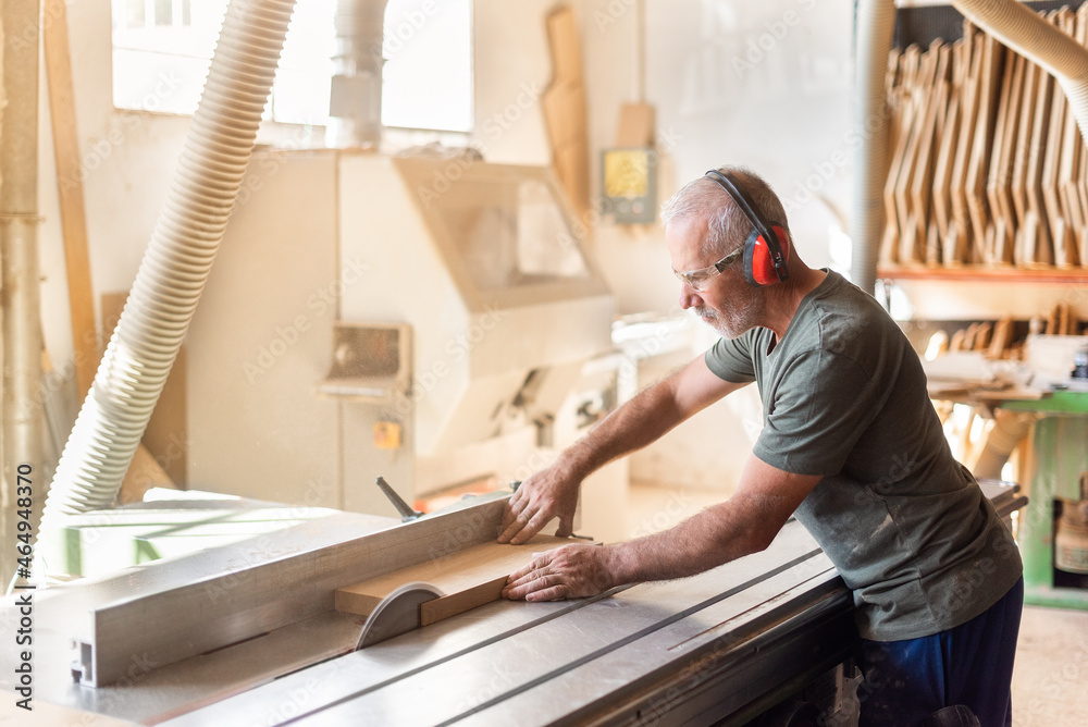 Man at work cutting timber on a sliding table saw Man at work cutting timber on a sliding table saw