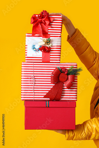 Man holding Christmas gift boxes on yellow background