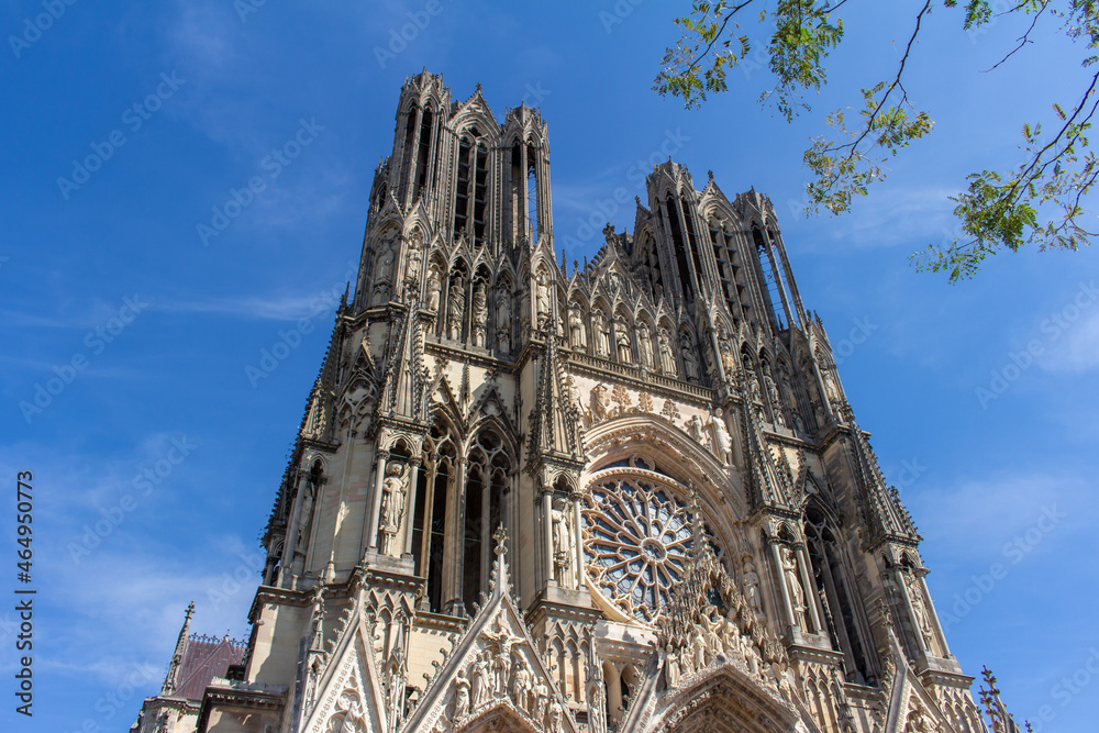 Landscape view of the ornate Our Lady of Reims Cathedral (Notre-Dame de Reims) in France, with trees in the foreground