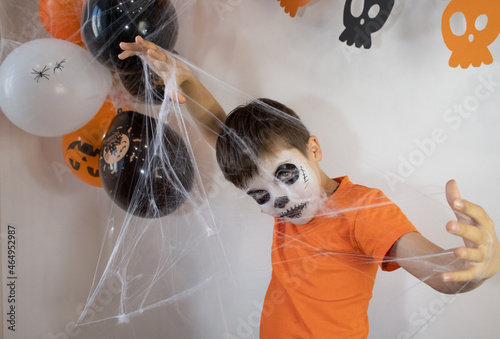 Happy baby with skeleton makeup. Spider web in the hands of a boy on Halloween