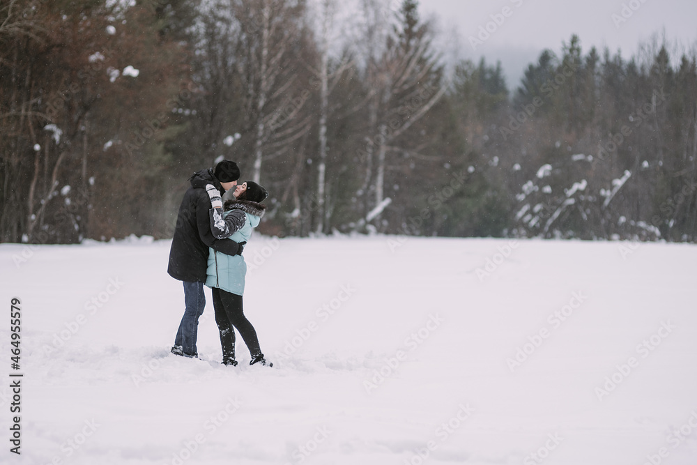 Loving couple of teenagers hugging and kissing in winter