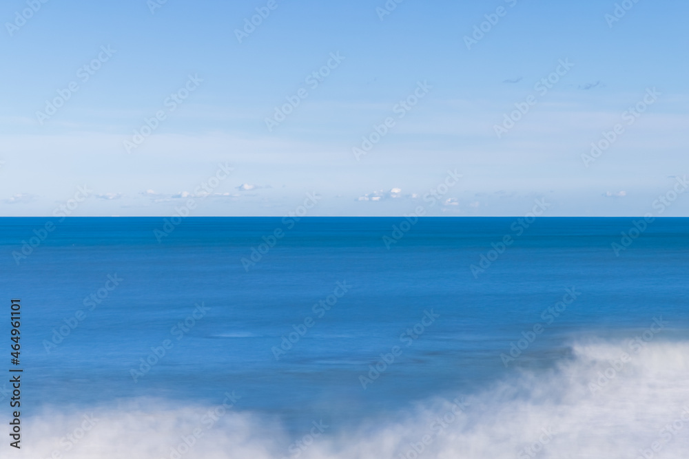 青い空と青い海が作る地平線と寄せる波が作る白い抽象、長秒露光