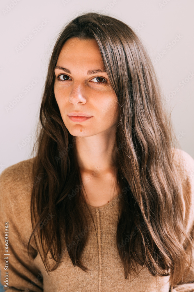 Millennial young pretty woman at home sitting on the couch. Confident and healthy portrait. Long brown hair and big eyes beautiful woman Millennial young pretty woman at home sitting on the couch. Confident and healthy portrait. Long brown hair and big eyes beautiful woman