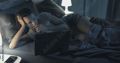 Woman lying in bed and connecting with her laptop