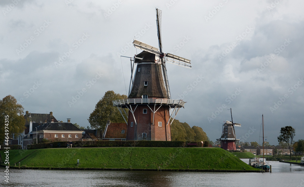 Two windmills on the bulwark of the old city Dokkum in the Netherlands on a dark and drizzly day in autumn