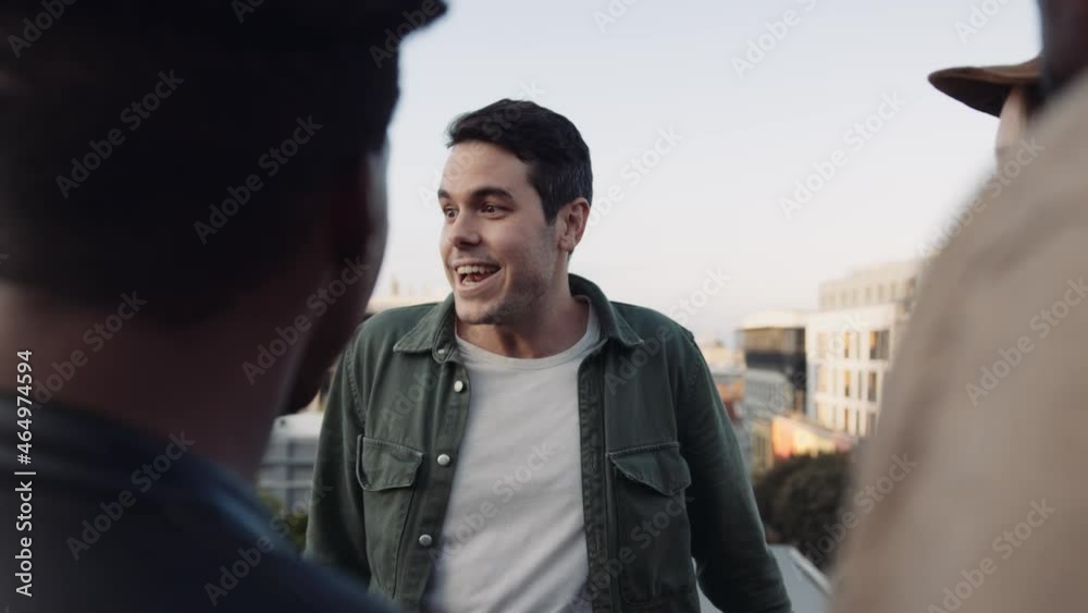 Adult Caucasian Male socializing with a diverse group of friends at rooftop party. Chatting lightheartedly at sunset. High quality image. Adult Caucasian Male socializing with a diverse group of friends at rooftop party. Chatting lightheartedly at sunset. High quality image.