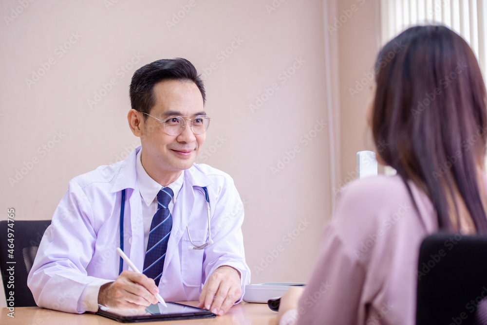 Doctor asking patient history, using a tablet to take notes, Asian woman. Doctor asking patient history, using a tablet to take notes, Asian woman.