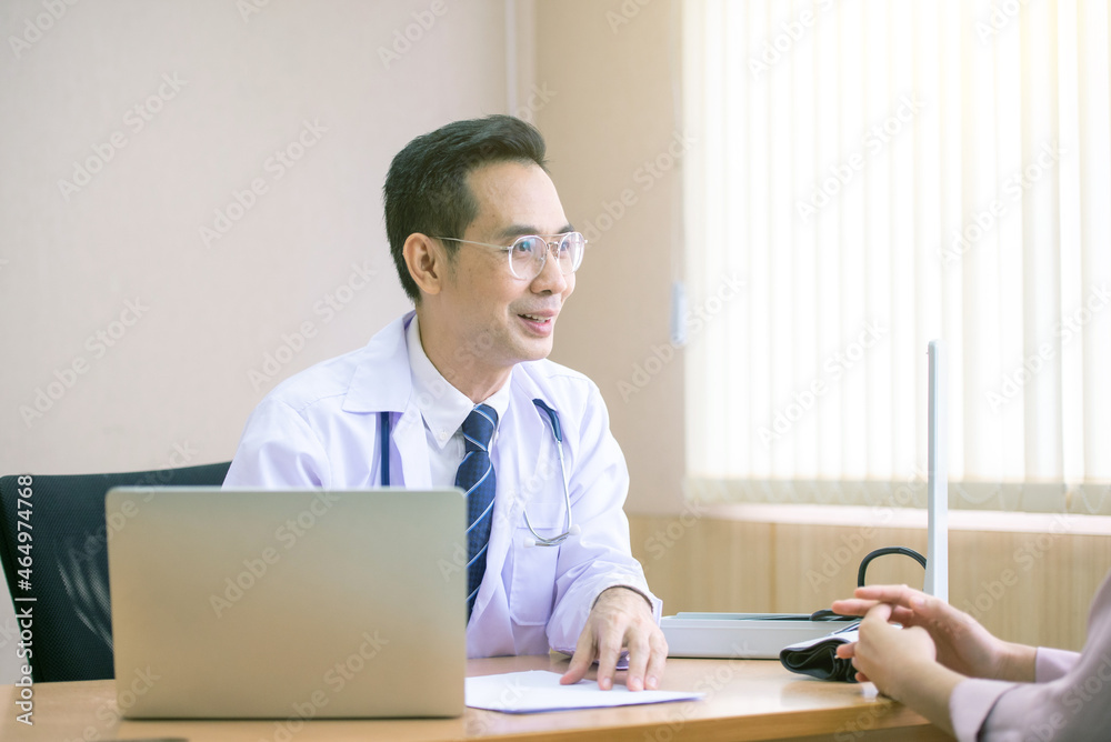 Doctor asking patient history, using laptop to take notes, Asian woman
