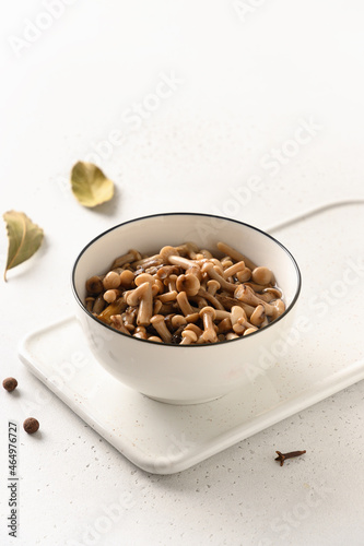 Pickled homemade honey mushrooms in white bowl on a white background. Close up. Vertical format.