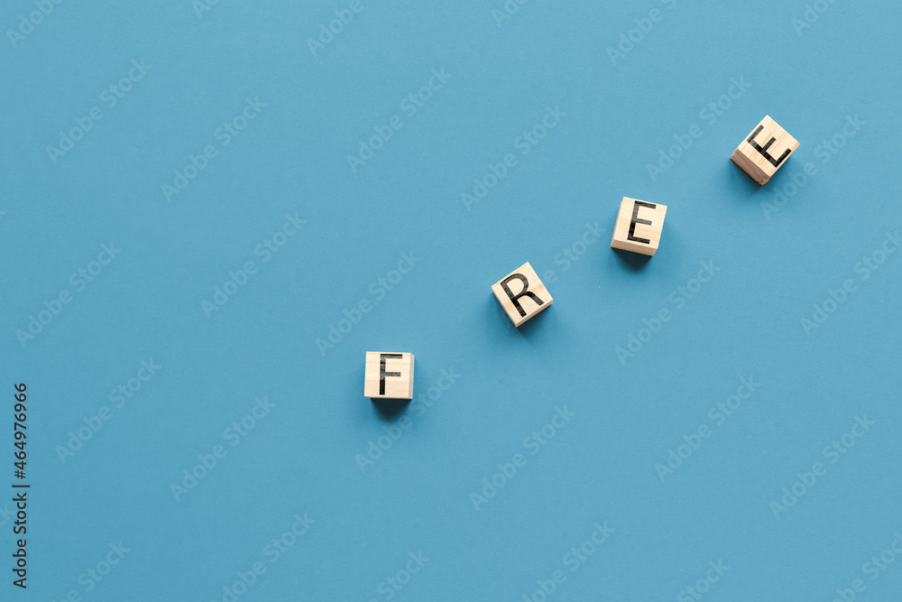 Fototapeta premium Wooden cubes with the inscription free on a blue background. Flat lay. Copy space. Business concept