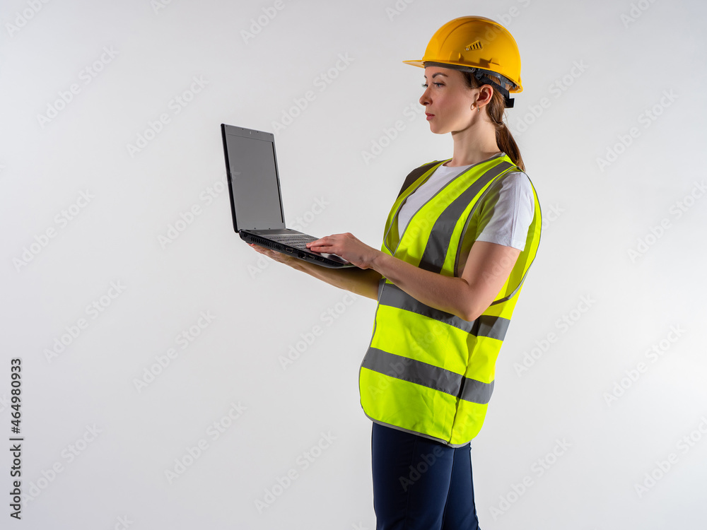 Woman inspector with a laptop in her hands. Girl inspector on a white background. She works as a reviewer somewhere. inspector with a computer in hand. Portrait of a girl in a yellow vest. Woman inspector with a laptop in her hands. Girl inspector on a white background. She works as a reviewer somewhere. inspector with a computer in hand. Portrait of a girl in a yellow vest.
