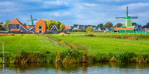 Panorama of a Dutch village with windmills, green houses pastures and meadows. Agricultural landscape. Tourism. Holland, Netherlands, Europe.