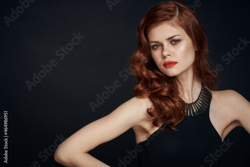 attractive red-haired woman in a black dress hairstyle dark background