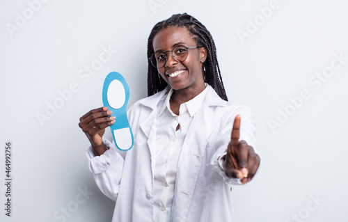 pretty black woman smiling proudly and confidently making number one. podiatrist concept