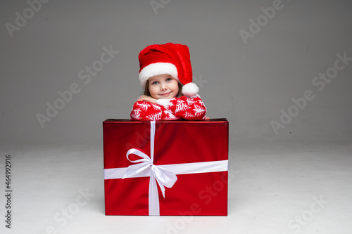 Adorable little girl in Santa hat with present.
