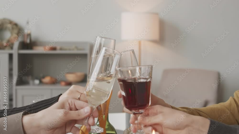 Tilting up of cropped friends with hands only in frame, clinking glasses with red and sparkling wine on Christmas Tilting up of cropped friends with hands only in frame, clinking glasses with red and sparkling wine on Christmas