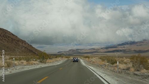 Road trip to Death Valley, driving auto in California, USA. Hitchhiking traveling in America. Highway, mountains and dry desert, arid climate wilderness. Passenger POV from car. Journey to Nevada.