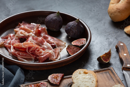 Jamon with figs and a baguette with cream cheese on the dining table, appetizer for wine, Spanish cooking.