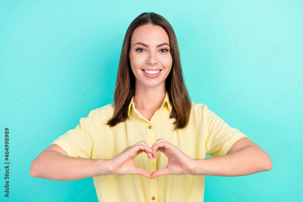 Photo of coquette young brunette lady show heart wear yellow blouse isolated on teal color background Photo of coquette young brunette lady show heart wear yellow blouse isolated on teal color background