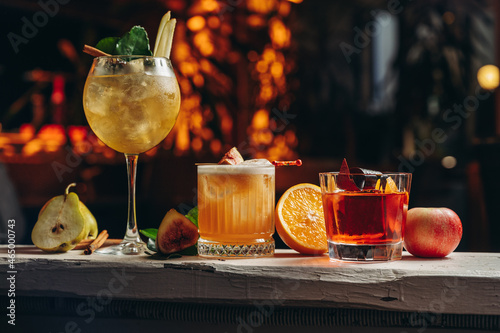 Three different beautiful cocktails in warm colors on a flower background