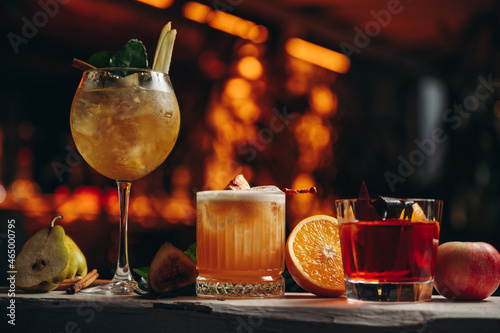 Three different beautiful cocktails in warm colors on a flower background