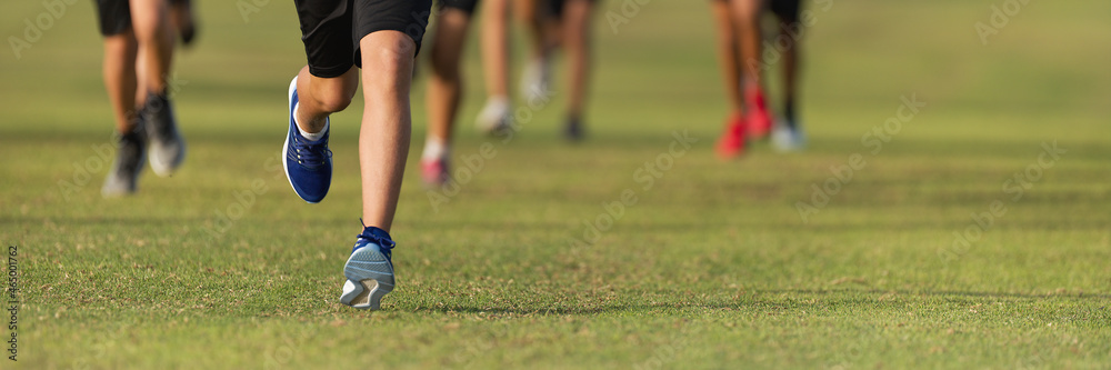 Running children, young athletes run in a kids run race, running on grass detail on legs, running in the light of morning Running children, young athletes run in a kids run race, running on grass detail on legs, running in the light of morning