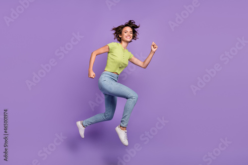 Photo of pretty beautiful young lady wear green t-shirt smiling jumping high running fast isolated violet color background