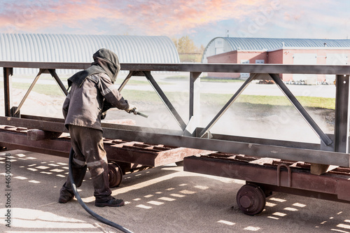 A worker in a special suit is sandblasting metal at an industrial site. photo