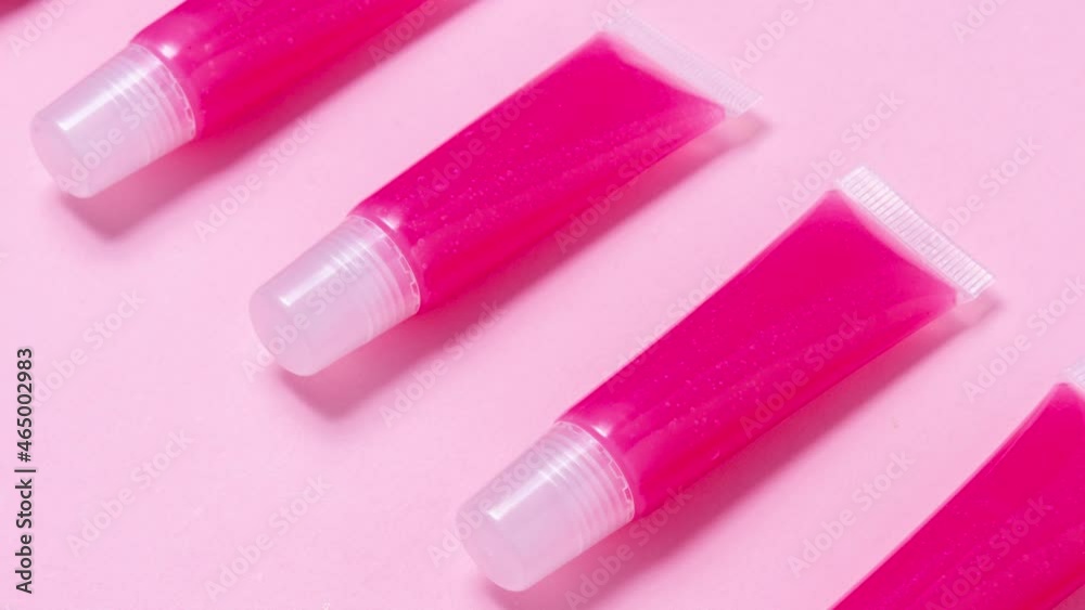 Lot of homemade lip glosses on pink background