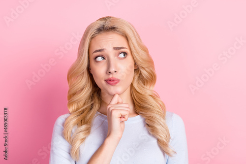 Photo of unhappy doubtful young woman look empty space think idea isolated on pastel pink color background